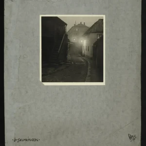 Photograph by Olaf Christoffersen from 1923 of a deserted Oslo street at twilight, with street lamps casting light through mist, creating a tranquil, melancholic scene.