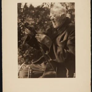 Photograph by Olaf Christoffersen of his grandfather holding a violin, capturing the weathered hands and serene focus of a life marked by hard work and music.