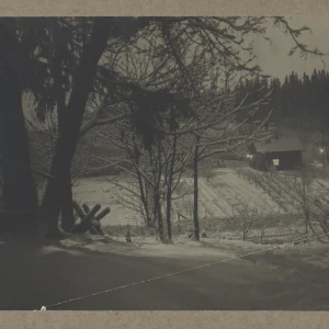 Photograph by Olaf Christoffersen of a snow-covered house illuminated on Christmas Eve, 1920, capturing the peaceful atmosphere of a winter night in the Norwegian countryside.