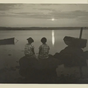 Photograph by Olaf Christoffersen of two children seated on a rock by the fjord in Asker, gazing towards Brønnøya under the evening sun.