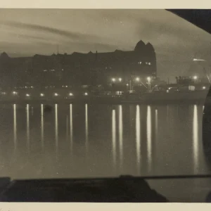 Photograph by Olaf Christoffersen of the Havnelageret building in Oslo at dusk, with lights reflecting across the calm harbor waters.